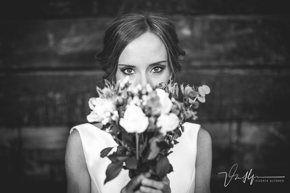 Retrato novia mirando a cámara entre el ramo de flores