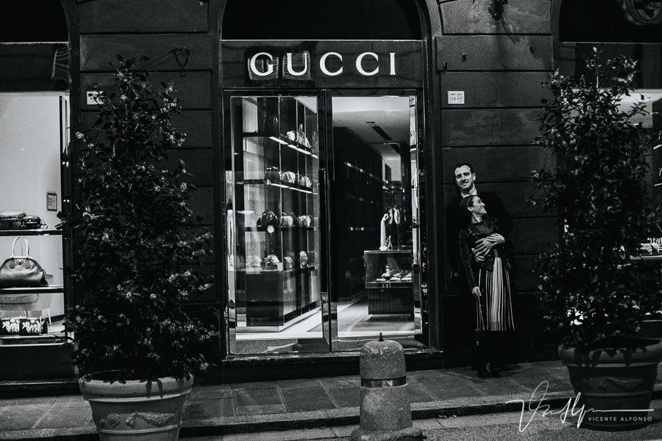 Pareja abrazándose junto a la tienda Gucci en Italia