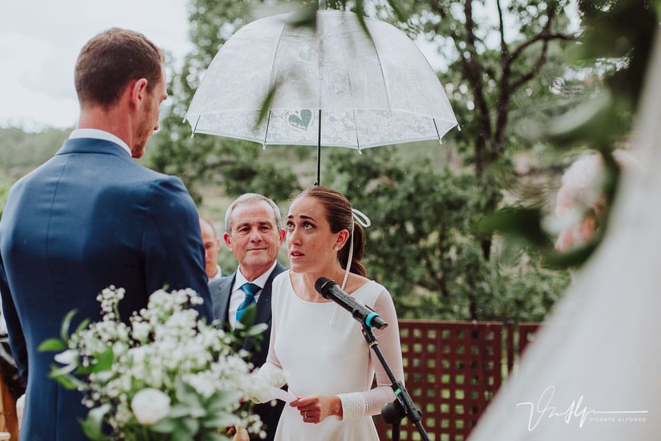 La novia leyendo amorosamente su lectura mientras su padre sujeta un paraguas