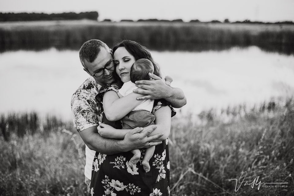 Reportajes familiares con padres abrazados y abrazando a su hijo recién nacido
