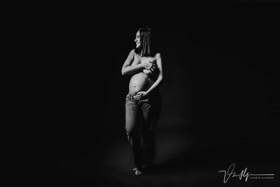 Mujer en vaqueros mostrando tripa embarazo