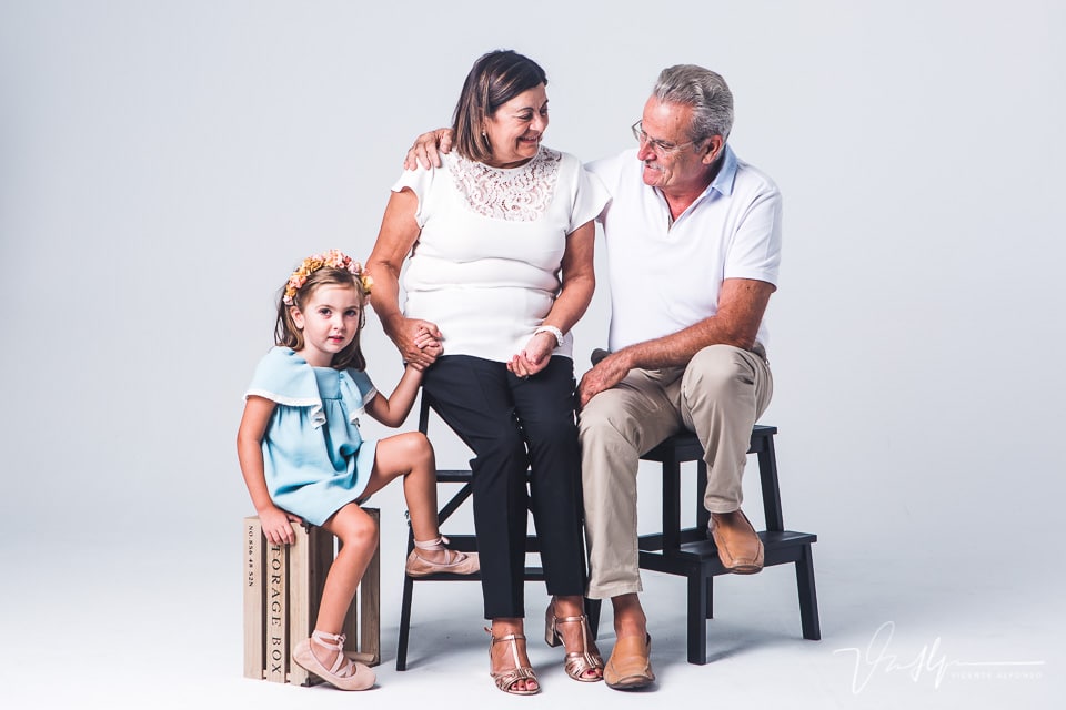Niña con sus abuelos sentados en un estudio de fotografía