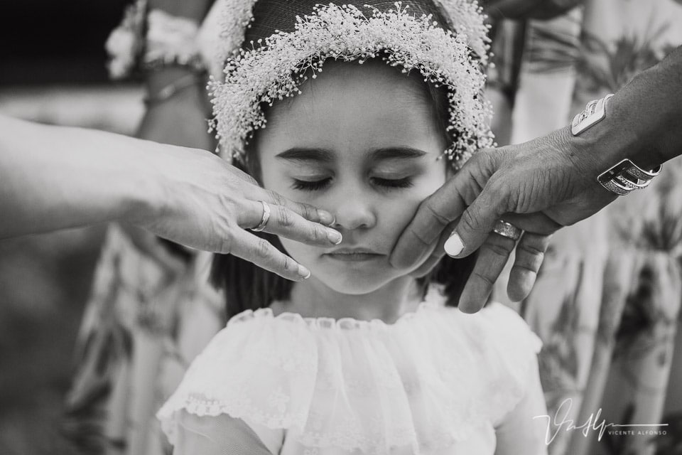 Retrato de niña mientras la acarician dos manos en una boda en Navalmoral