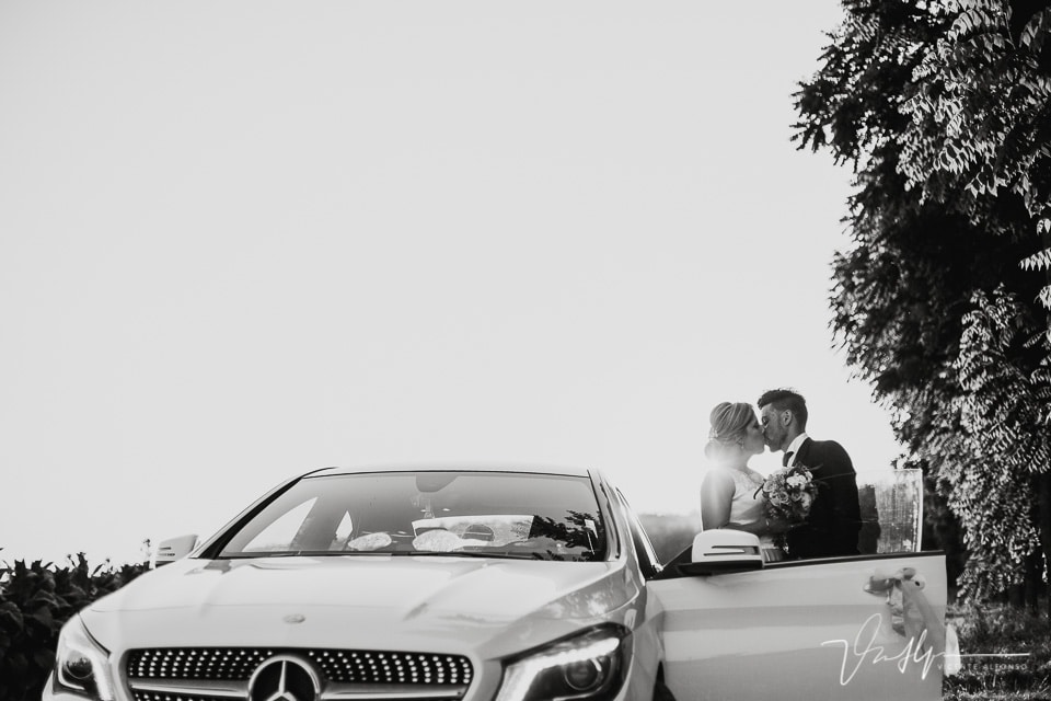 Novios besándose junto al Mercedes
