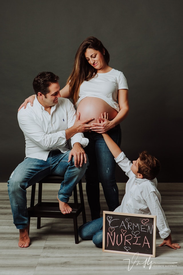 Reportajes familiar de embarazo, con su hijo y marido y una pizarra