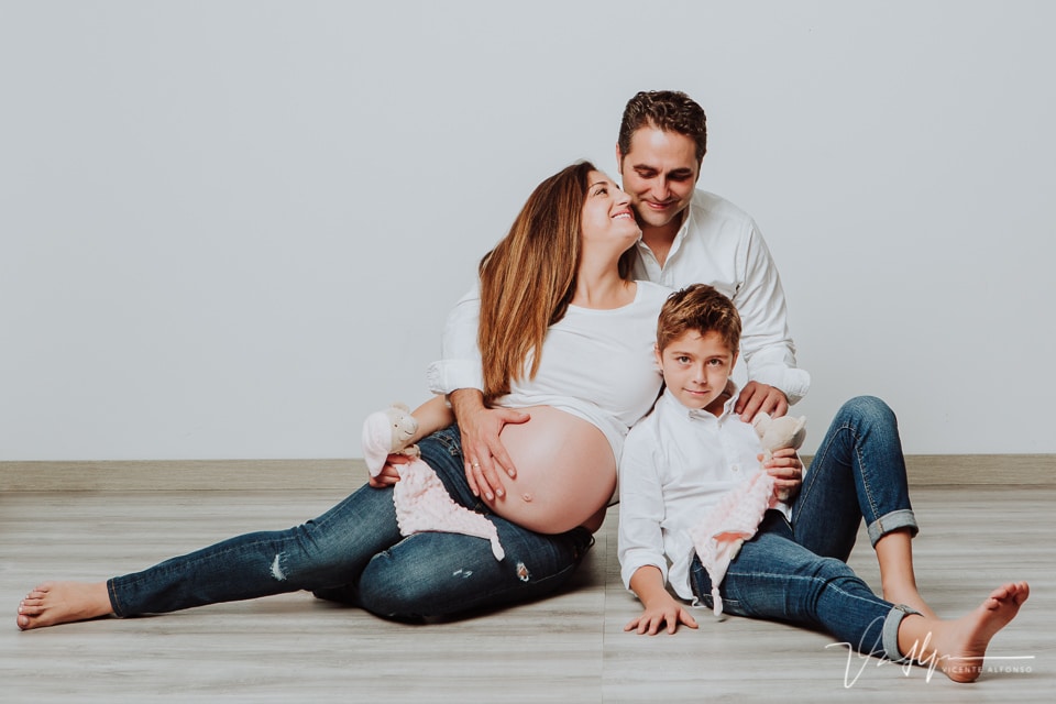 Reportajes familiar de embarazo, con su hijo y marido sentados en el suelo