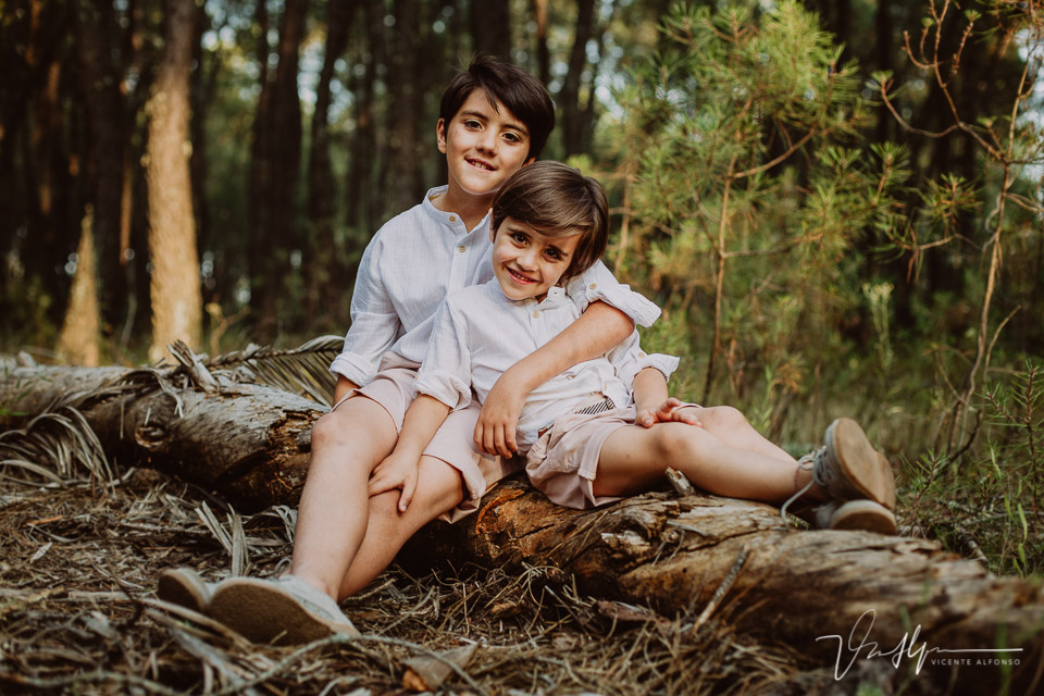 Fotografía de dos hermanos posando en un tronco